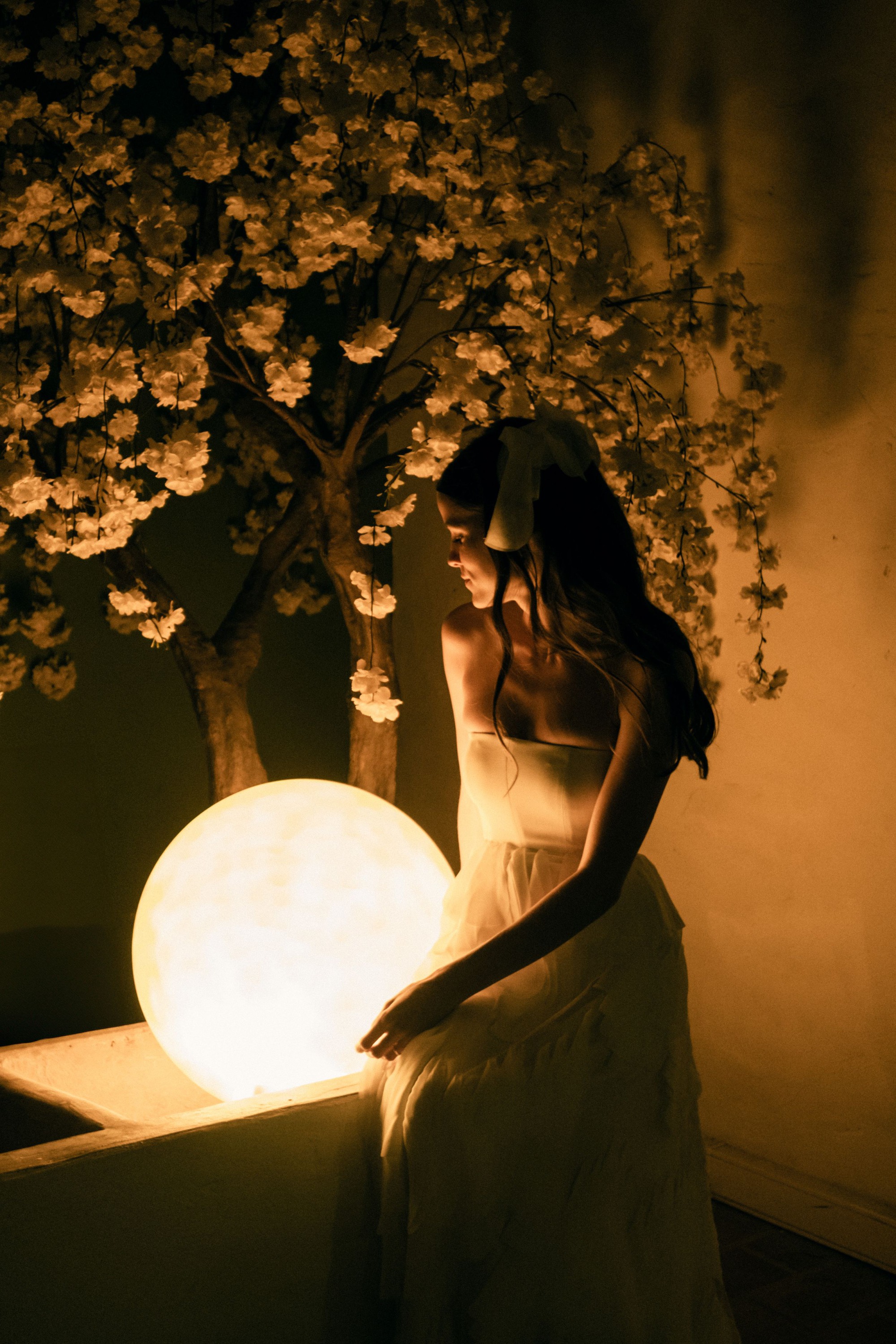 Ethereal scene with glowing orb light and cherry blossoms creating a magical atmosphere.